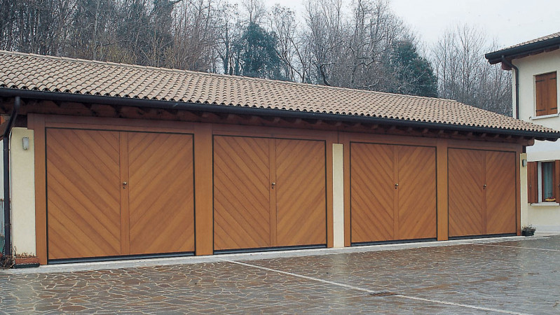 Porta basculante in legno: la bellezza della tradizione. Disponibilità di tanti disegni pantografati con finitura in 8 colorazioni effetto legno.